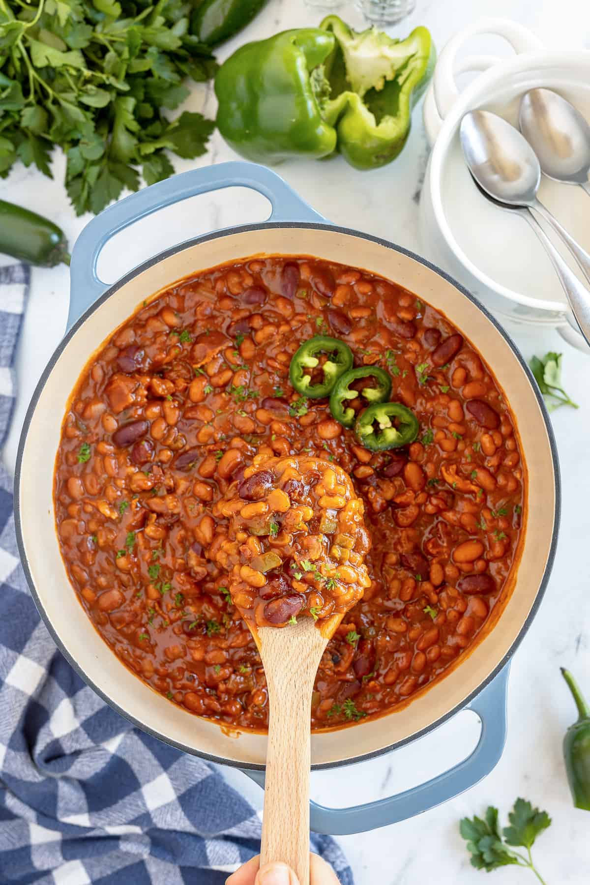 A wooden spoon with a scoop of baked beans hovering