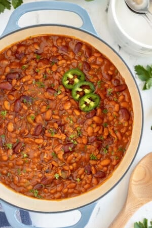 A close up shot of a pot of baked beans with jalapeno slices.