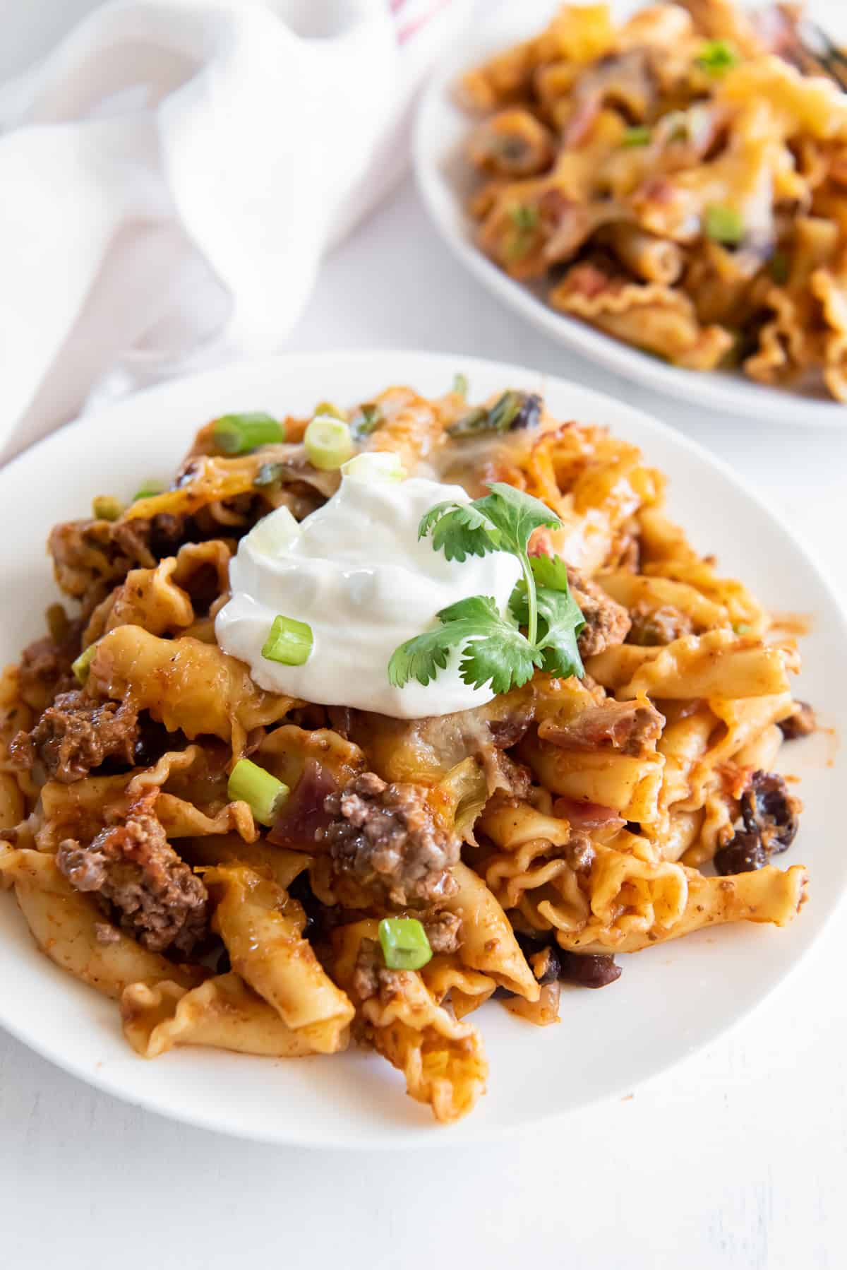 A serving of Taco Pasta Bake on a white plate topped with sour cream.
