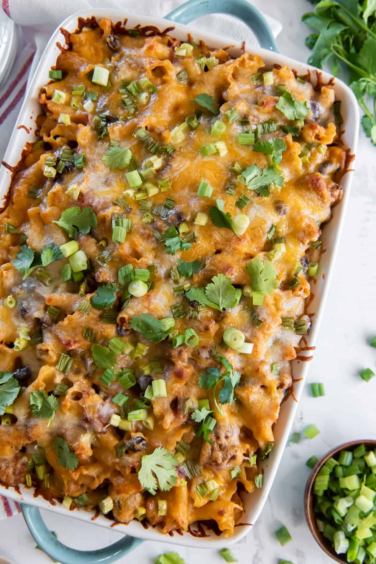 A top down shot of a taco casserole topped with cheese and green onion.