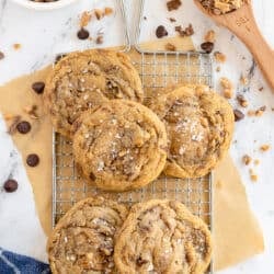 A top down shot of cookies on a wire rack with chocolate chips and toffee bits.