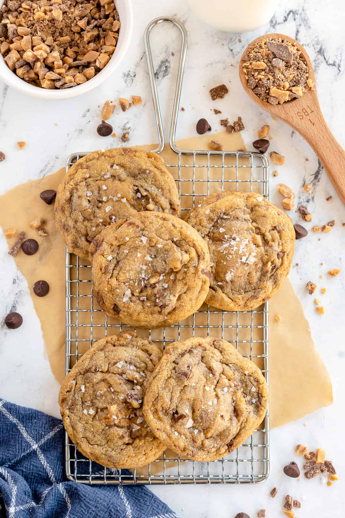 A top down shot of cookies on a wire rack with chocolate chips and toffee bits.