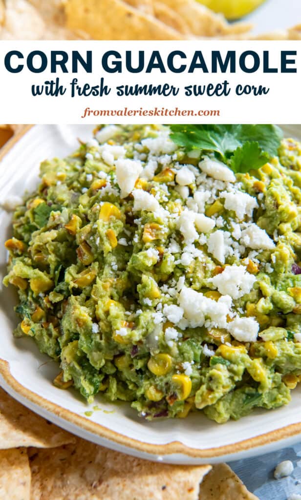 Corn guacamole in a white bowl surrounded by tortilla chips with text.