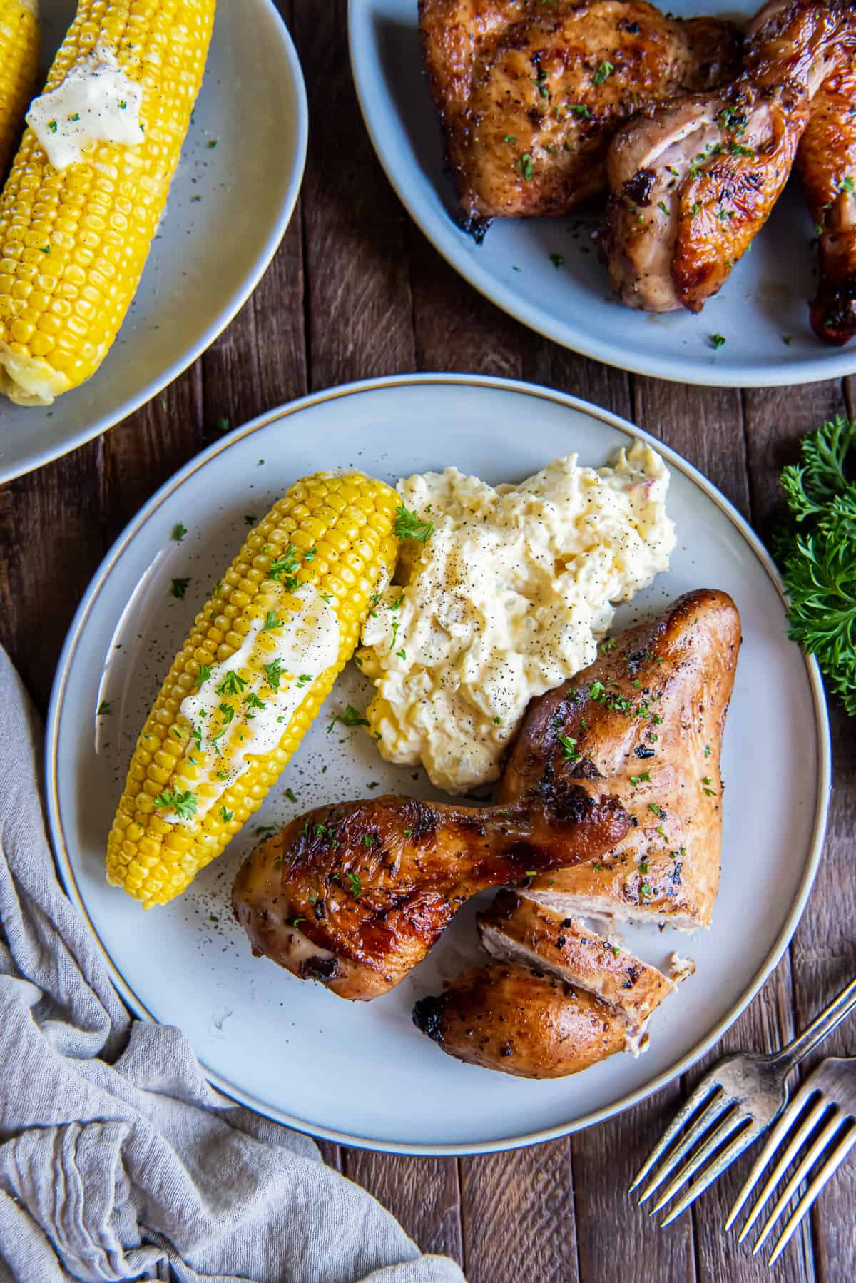 A top down shot of a plate of grilled chicken with corn and potatoes.