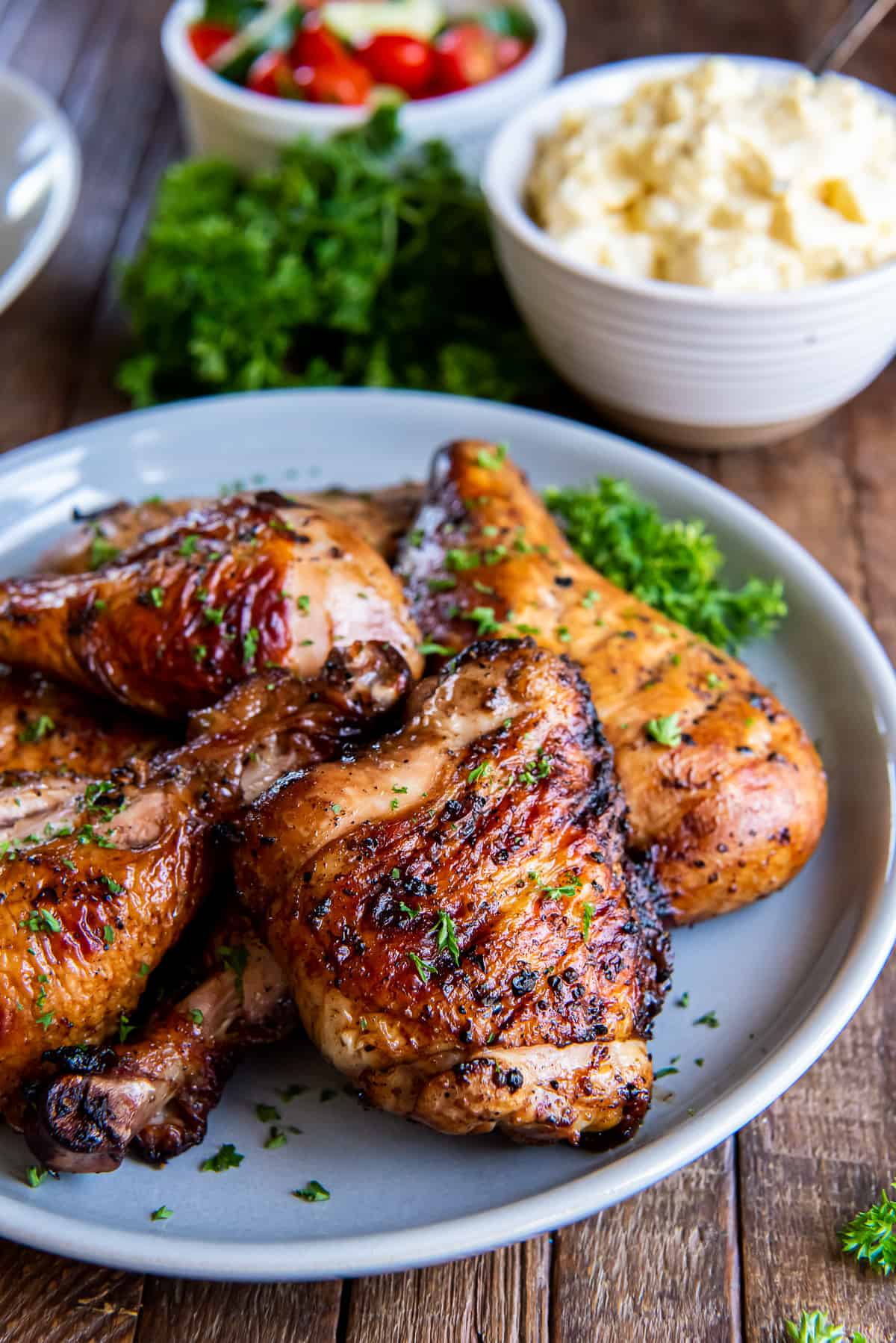 Grilled chicken on a white plate on a brown board.