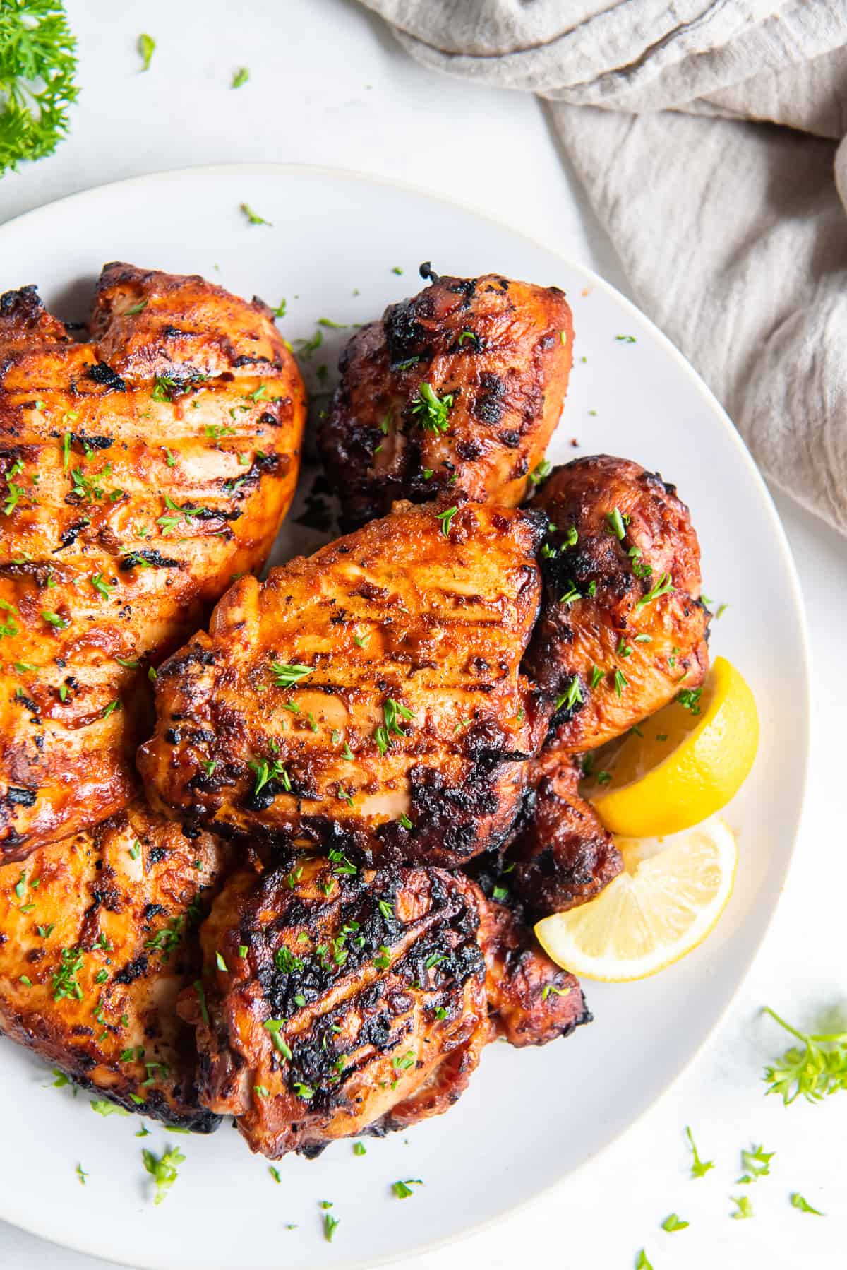 A top down shot of Grilled Paprika Chicken on a plate with lemon wedges.