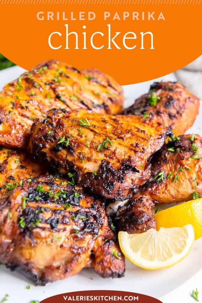 Grilled paprika chicken piled on a white plate with lemon wedges with text overlay.