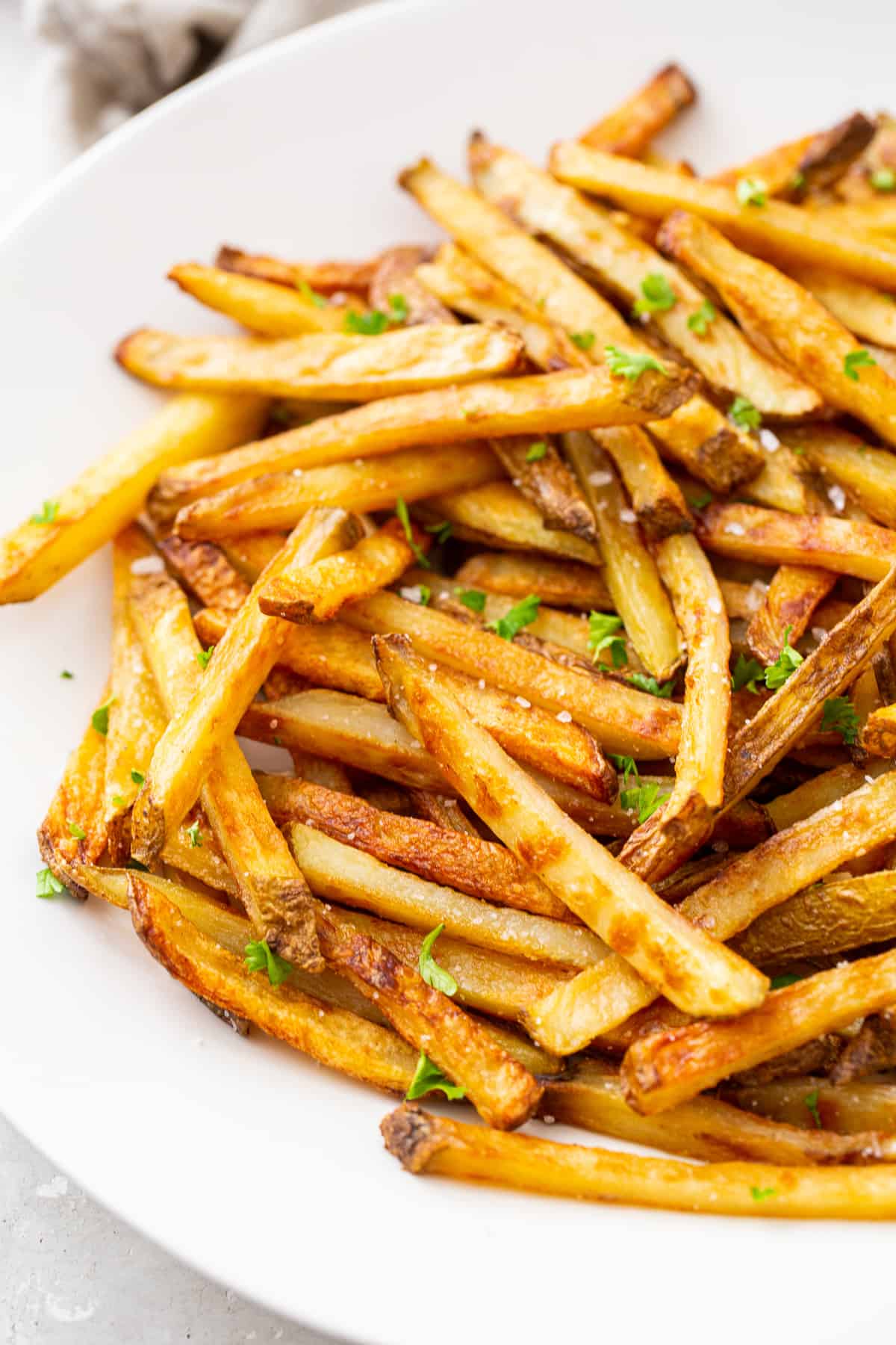 A close up of baked french fries in a white bowl.