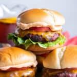 Three burgers on brioche buns stacked on a platter.