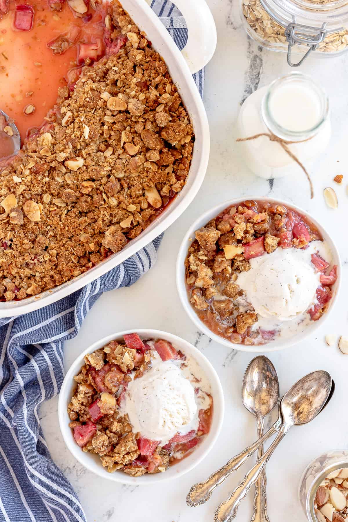 A top down shot of two bowls of rhubarb crisp with melting ice cream.