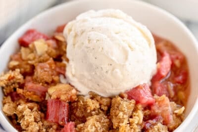 Rhubarb crumble in white bowls topped with vanilla ice cream.