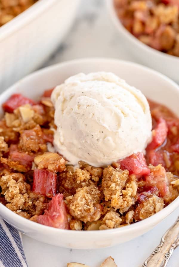 Rhubarb crumble in white bowls topped with vanilla ice cream.