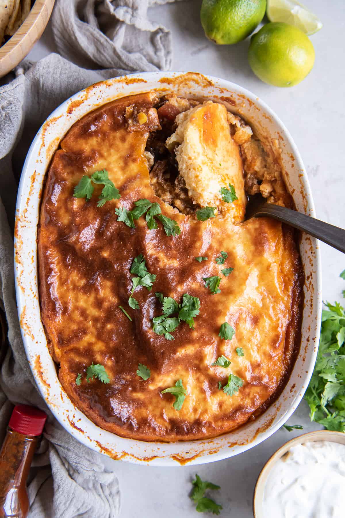 A top down shot of a spoon resting in a casserole of tamale pie.