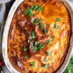 A top down shot of a browned cornmeal crust on tamale pie in a white casserole dish.