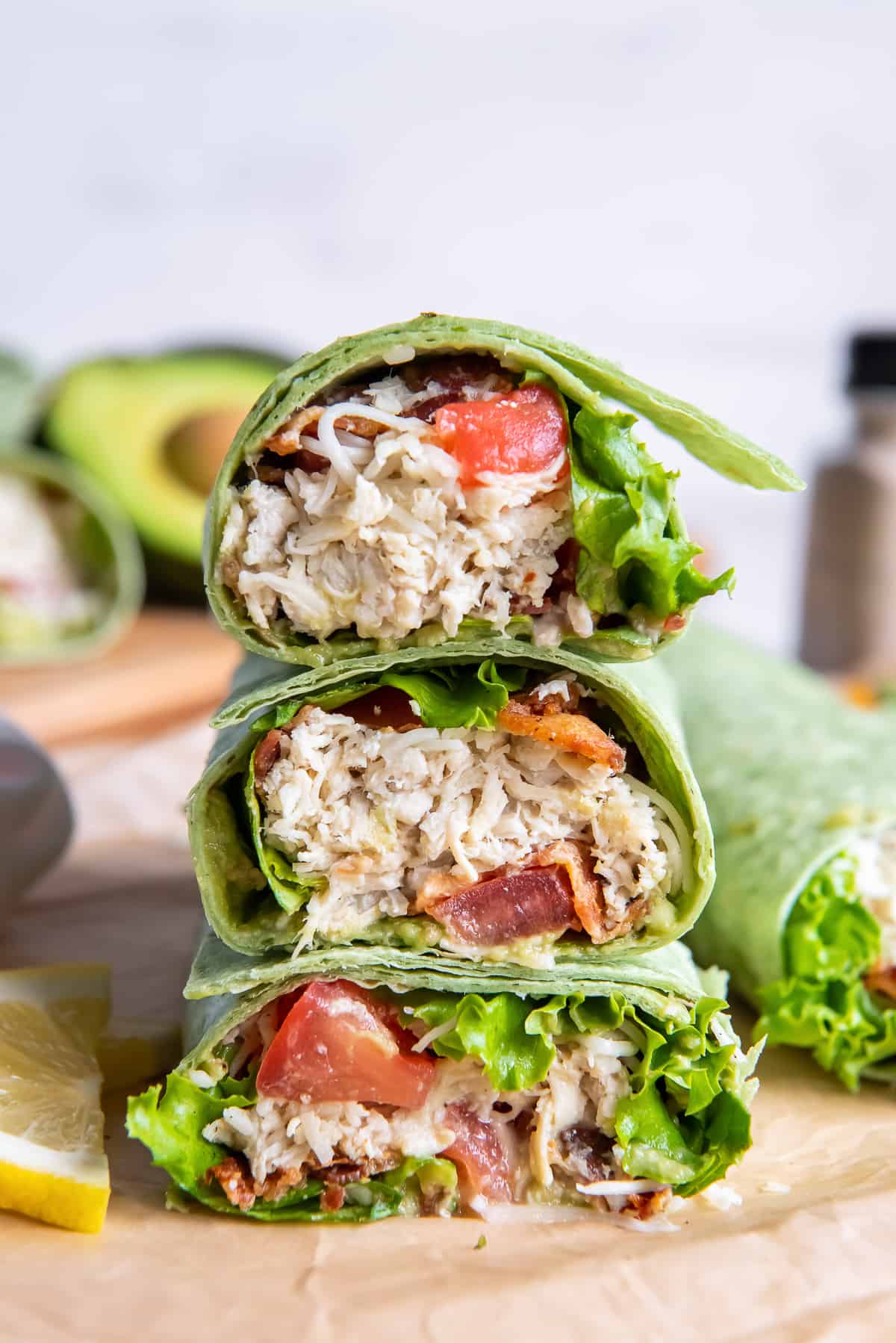 A California Club Wrap on a green tortilla sliced in half and stacked on a cutting board.