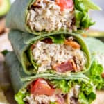 A chicken wrap on green tortilla sliced in half and stacked on a cutting board.