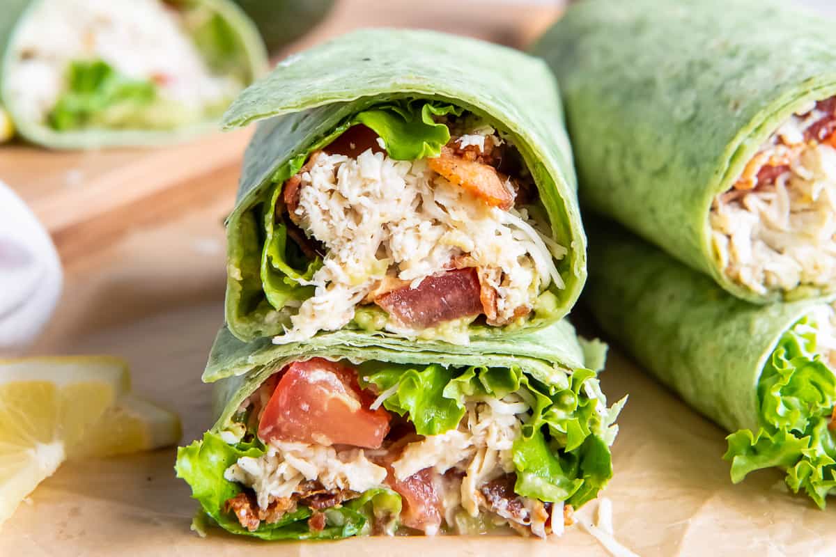 A California Club Wrap sliced in half and stacked on a cutting board.