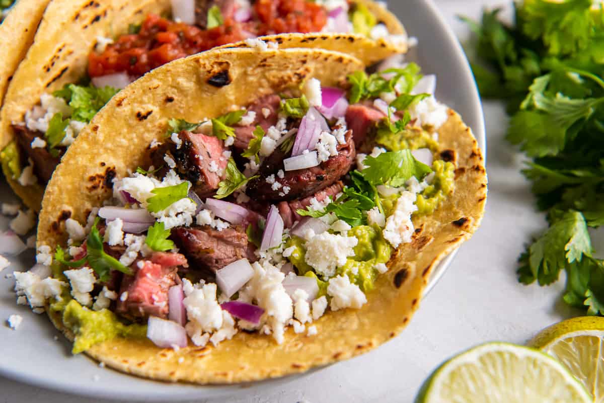 A carne asada taco on a corn tortilla with red onion and cotija cheese.