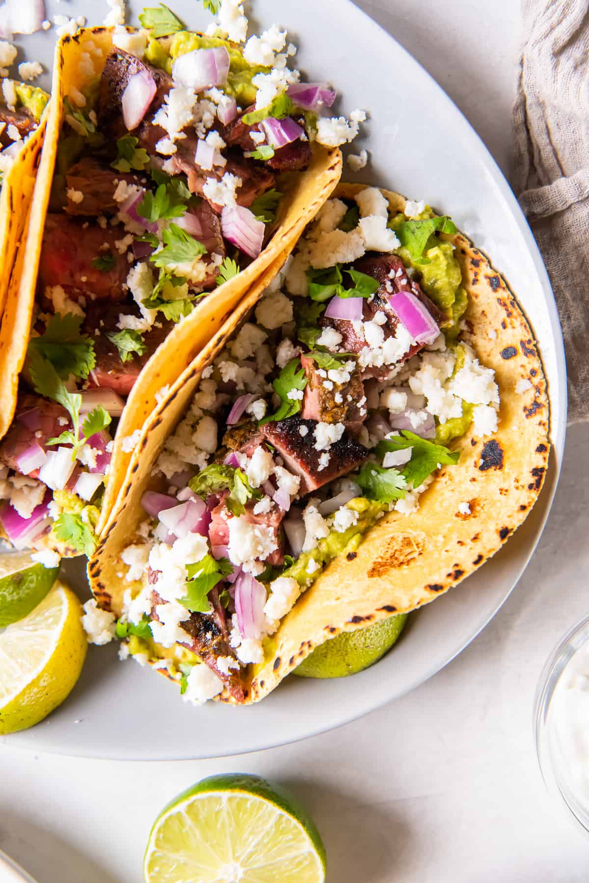 A top down shot of a carne asada taco on a corn tortilla with red onion, cilantro and cotija cheese.