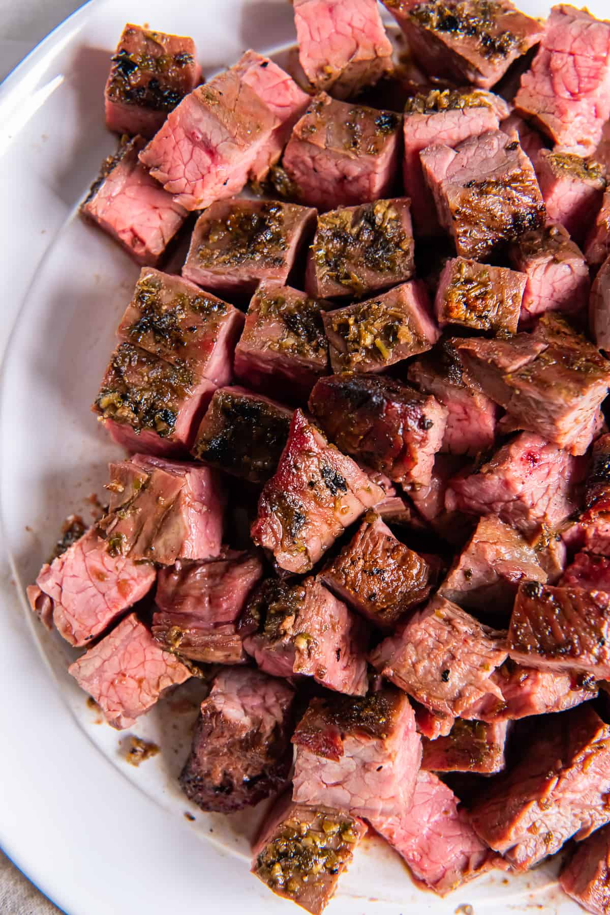 Chopped pieces of carne asada on white platter.