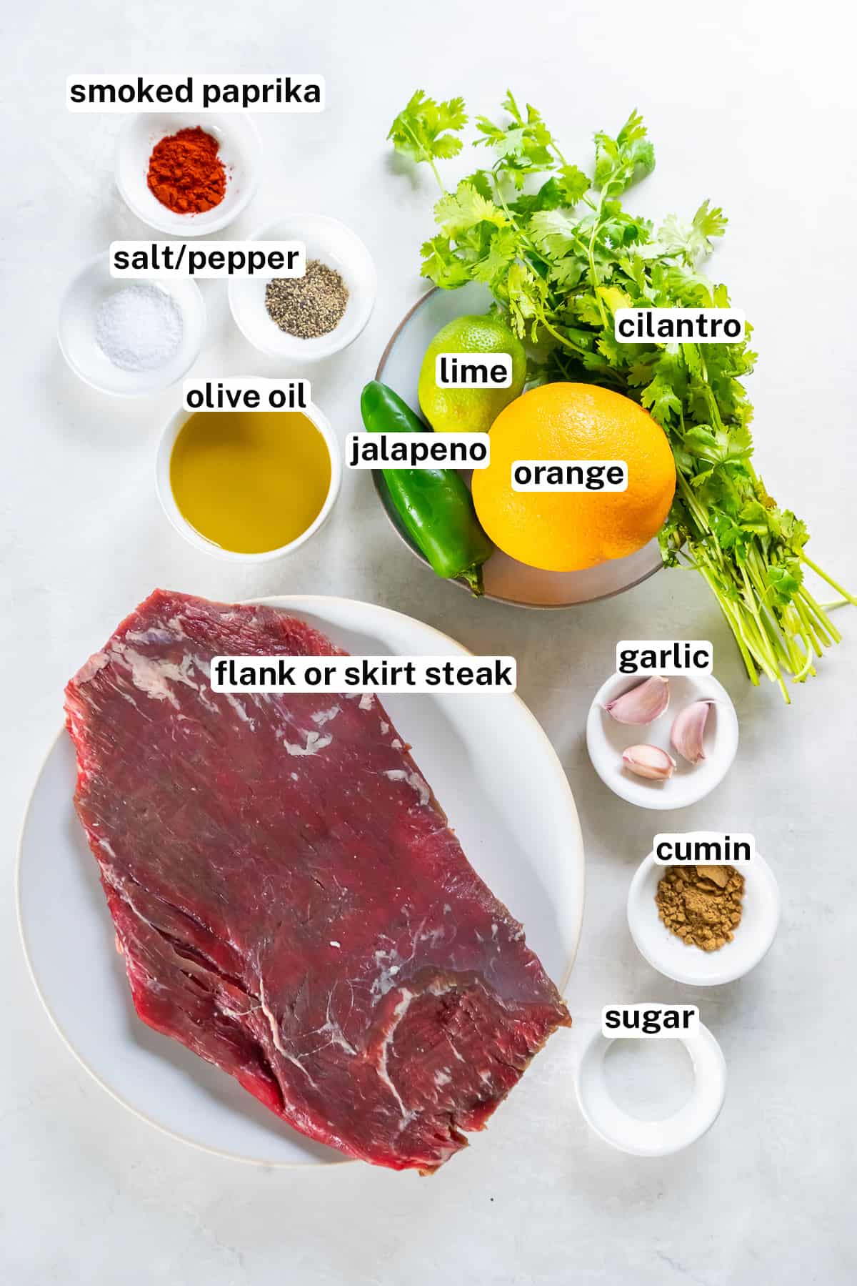 A flank steak and other ingredients to make carne asada.