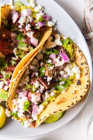 A top down shot of a carne asada taco on a white plate.