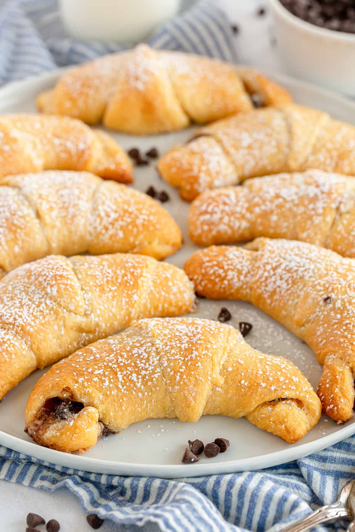 Chocolate filled crescent rolls topped with powdered sugar on a white platter.