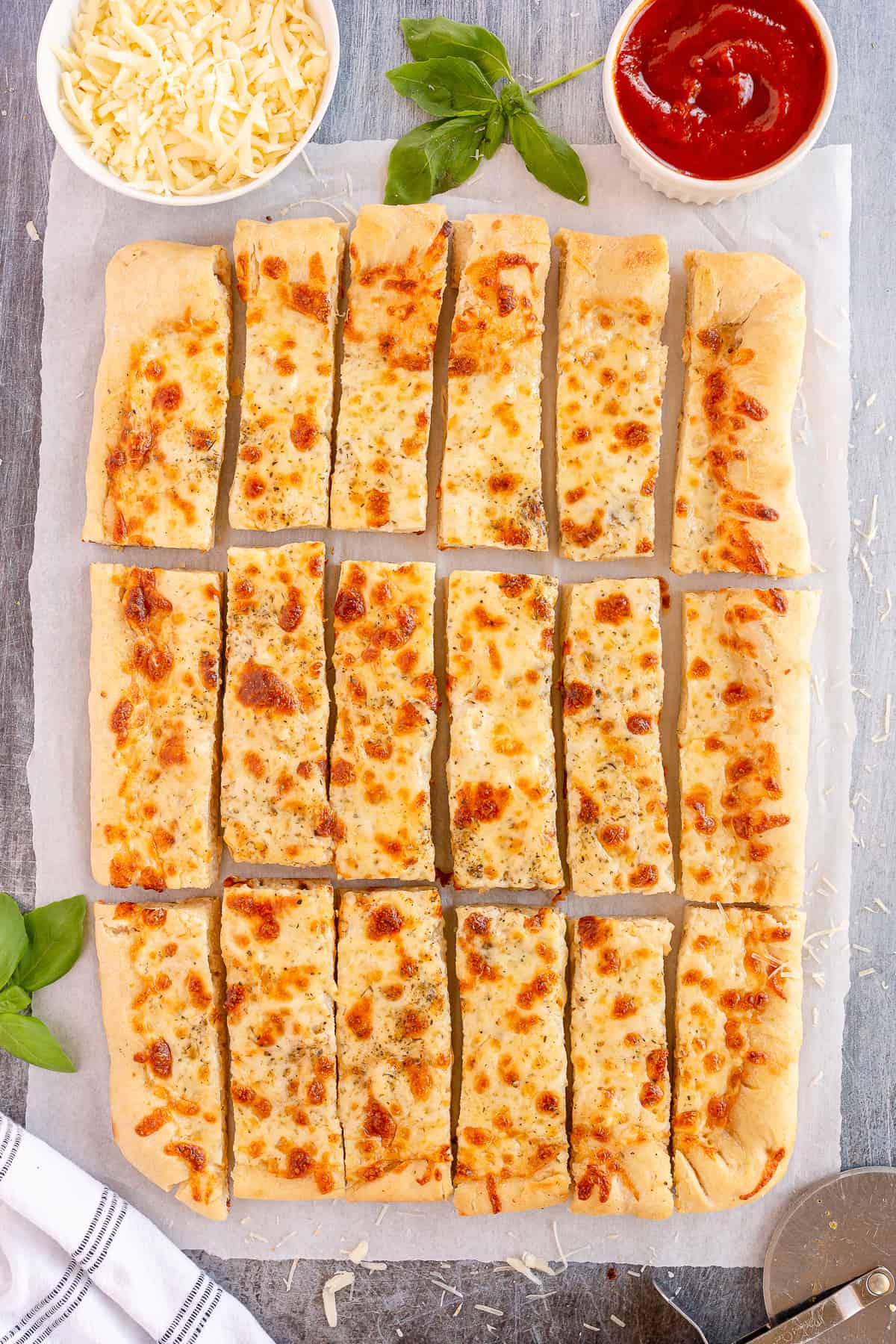 Sliced breadsticks with melted cheese on parchment paper.