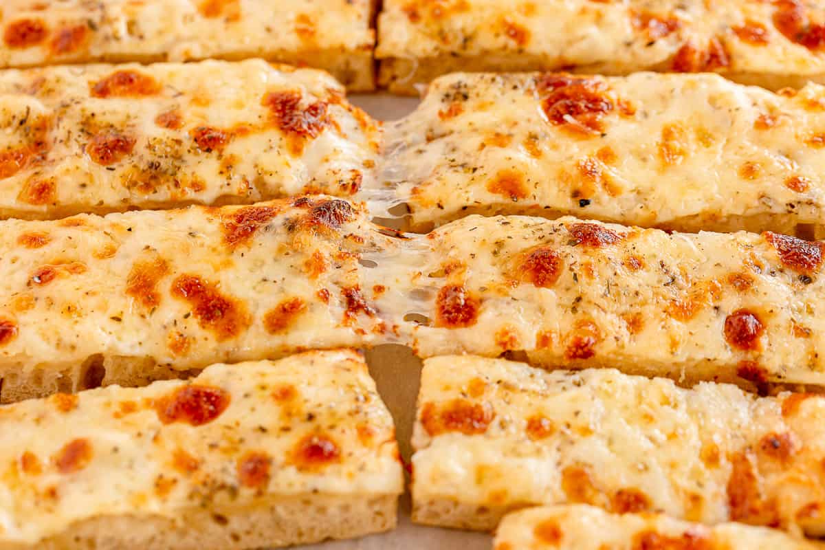 Strings of cheese pull between breadsticks.