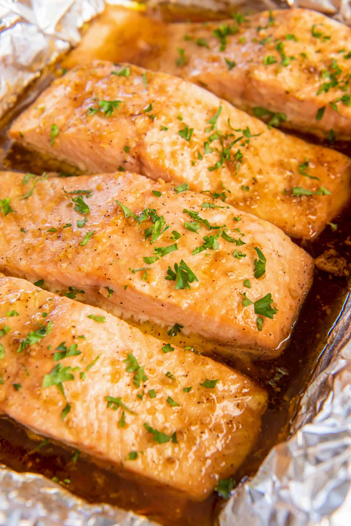 Roasted salmon topped with parsley in a foil lined baking dish.