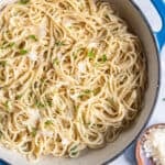 Parmesan Noodles in a blue skillet next to a small bowl of Parmesan.