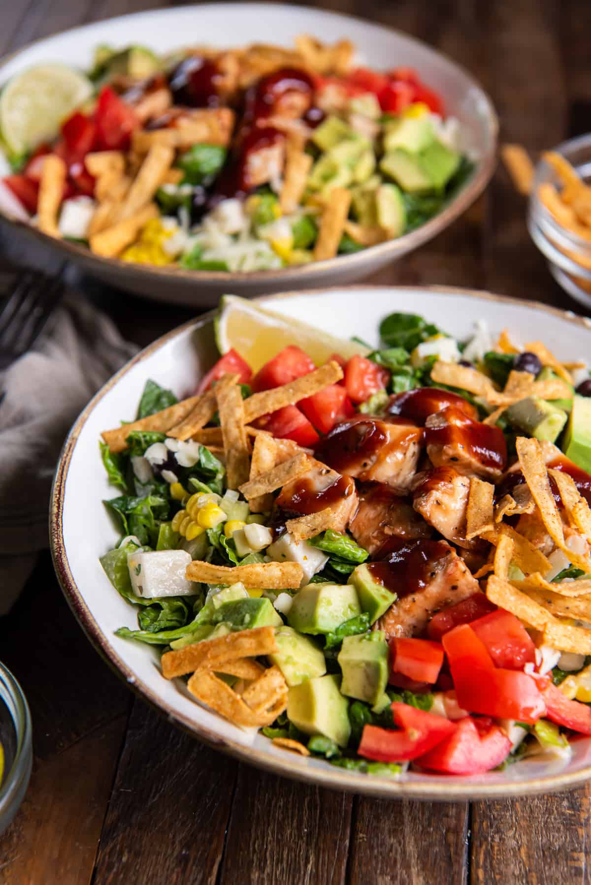 Two bowl of BBQ Chicken Salad with tomatoes, cheese, and tortilla strips.