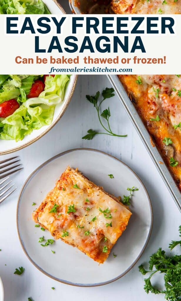 A top down shot of a lasagna in a metal pan next to a green salad and a slice of lasagna on a small white plate with text.