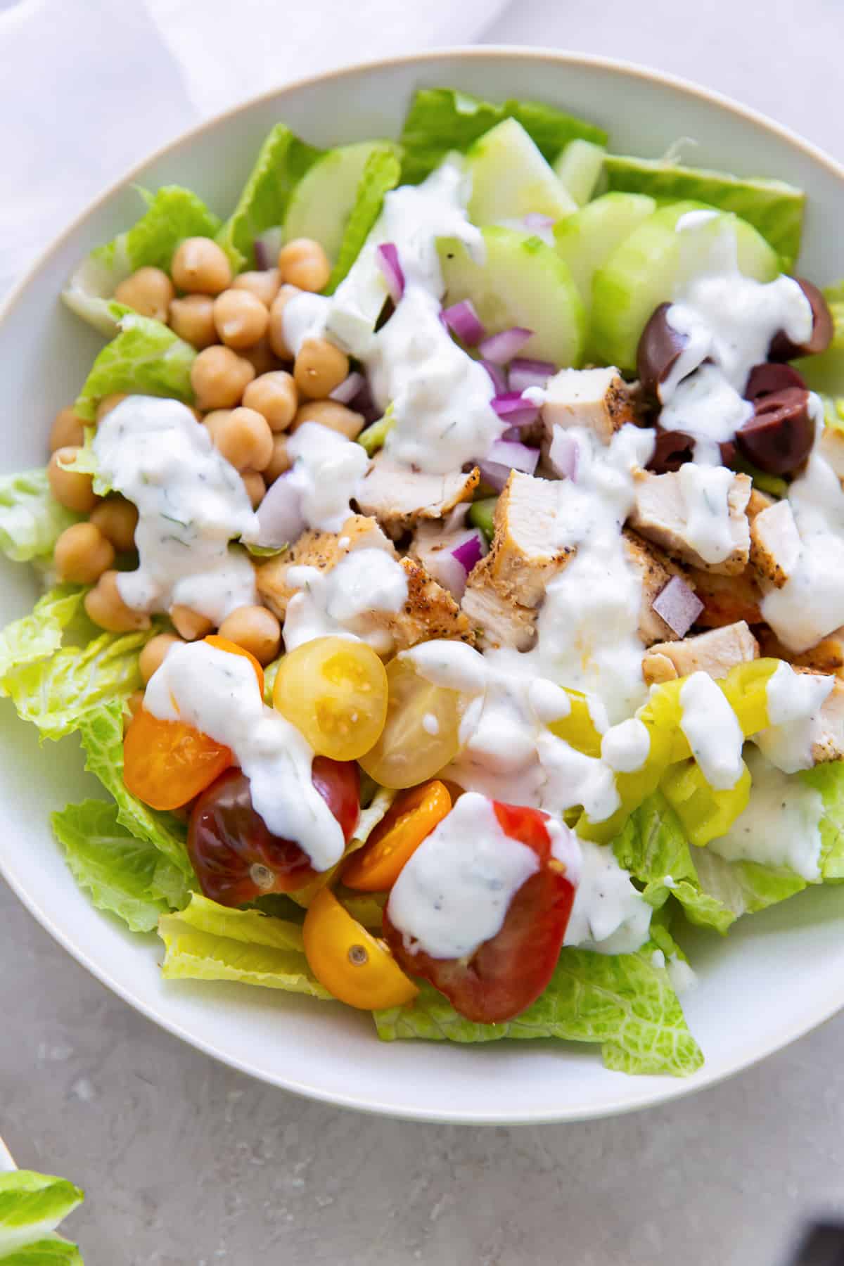 Salad topped with creamy feta dill dressing in a small white salad bowl.