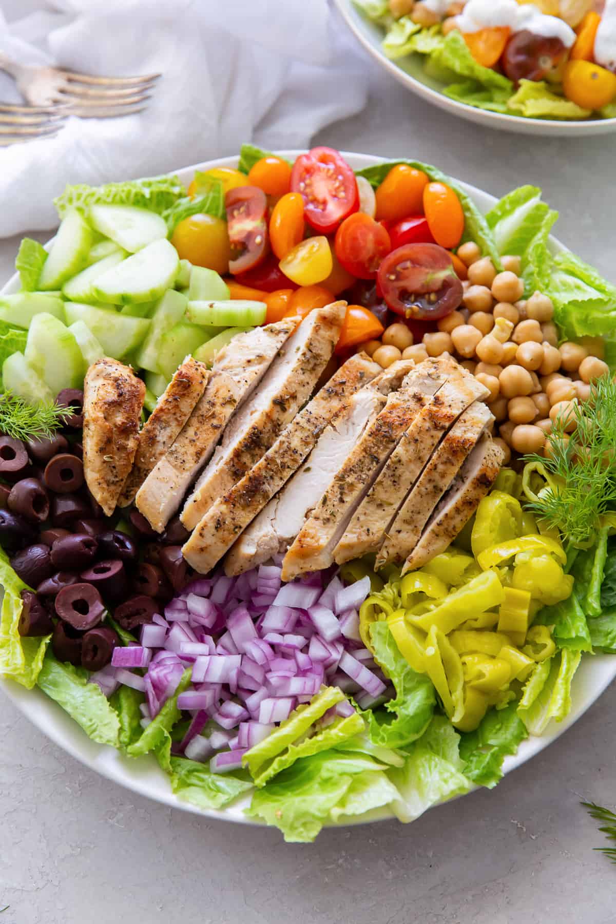 Mediterranean Chicken Salad with kalamata olives, cherry tomatoes, red onion, pepperoncini in a wide shallow bowl.