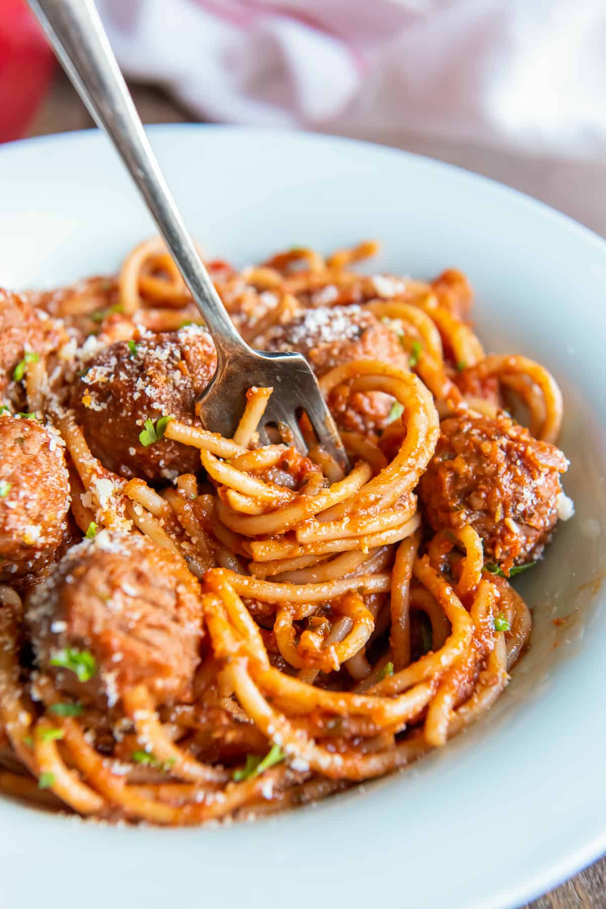 A fork twirling spaghetti in a white bowl.