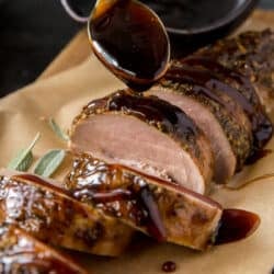 Balsamic glaze drizzling off a spoon on to sliced pork tenderloin.