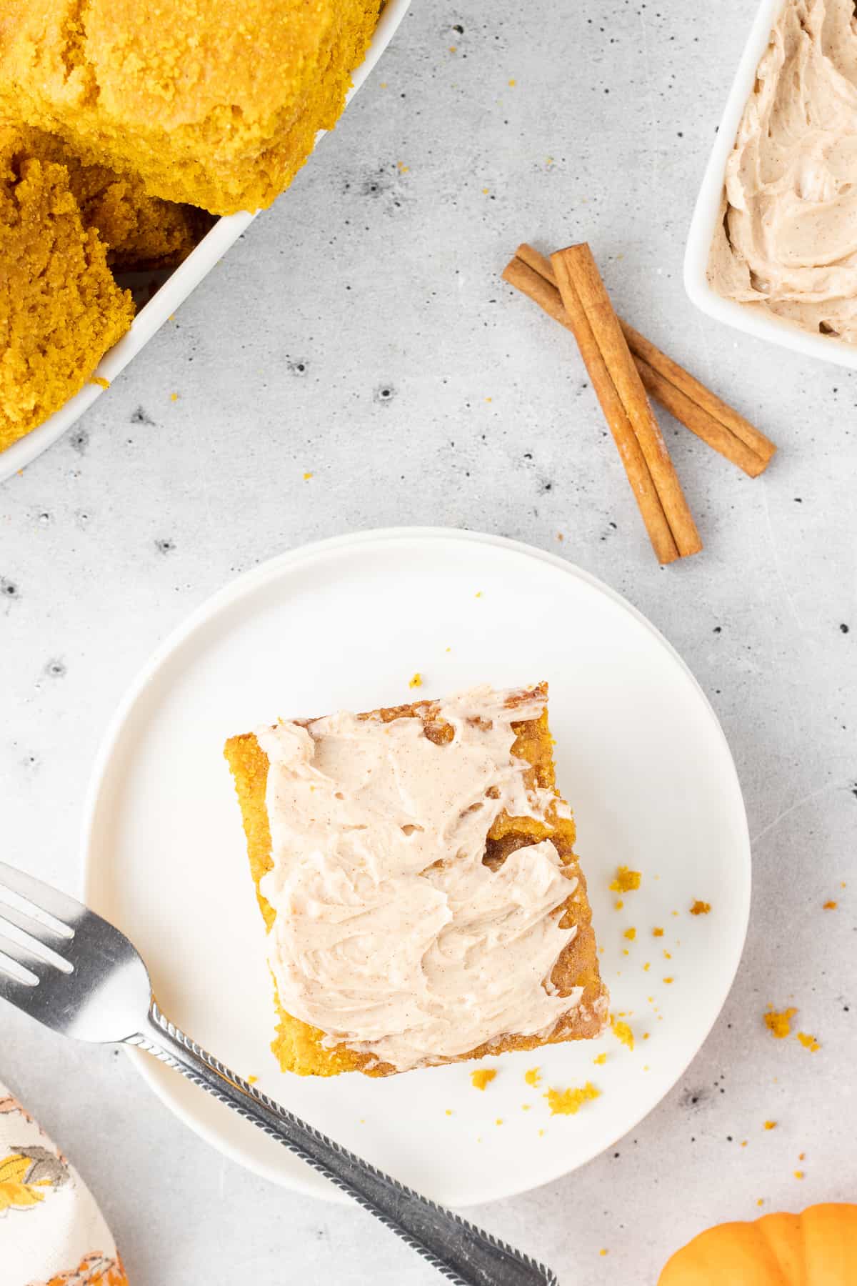 A top down shot of a slice of cinnamon honey butter spread over the top of a slice of pumpkin cornbread on a white plate.