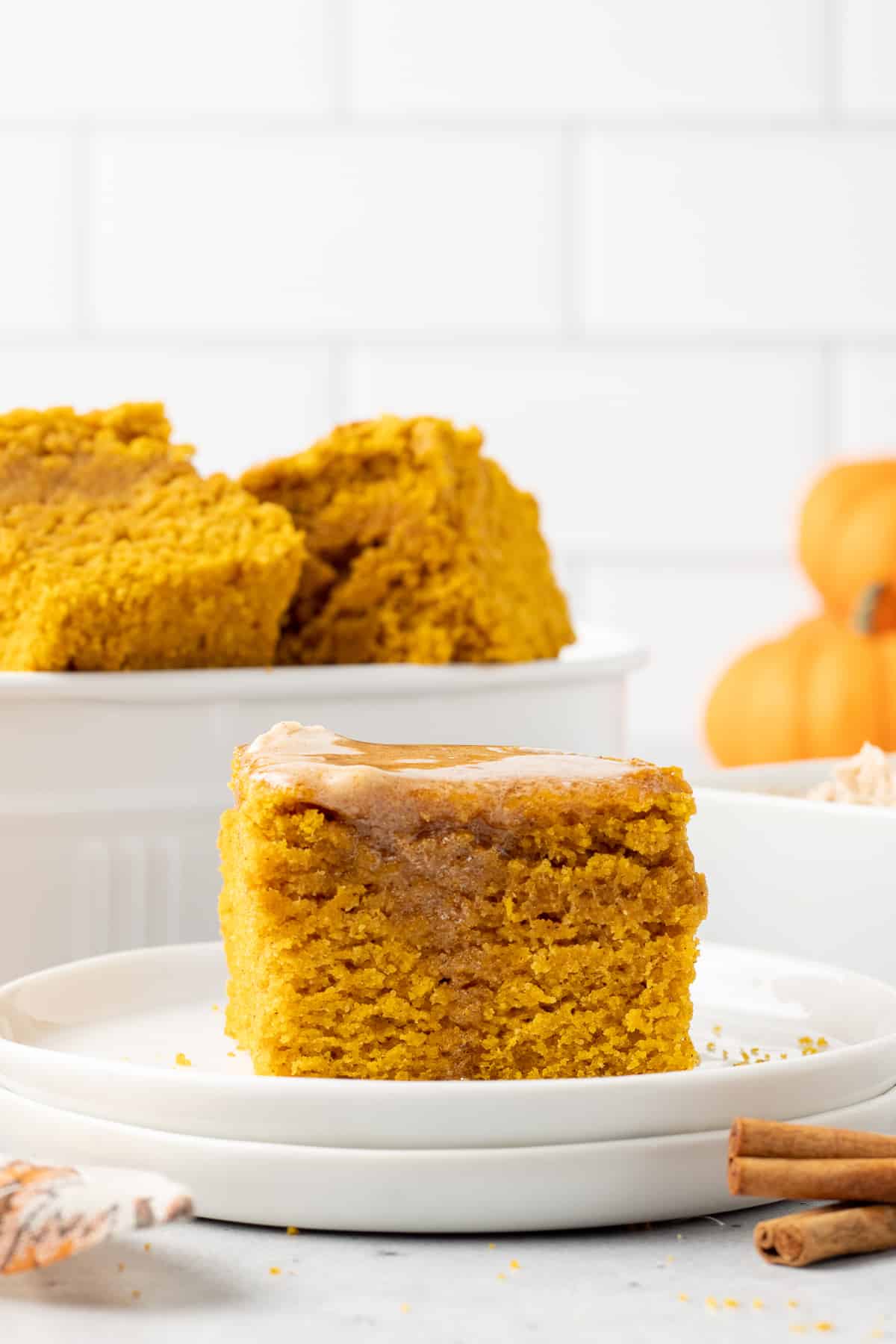 A slice of pumpkin cornbread with melted cinnamon honey butter on a white plate.
