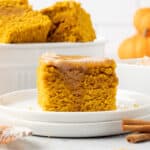 A slice of pumpkin cornbread with melted cinnamon honey butter on a white plate.