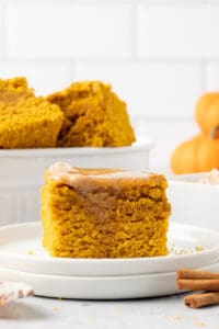 A slice of pumpkin cornbread with melted cinnamon honey butter on a white plate.