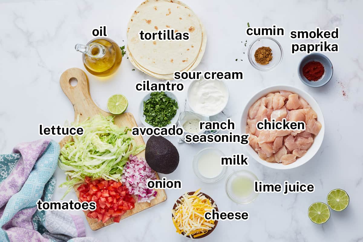 Chicken, tortillas and other ingredients on a grey surface with text.