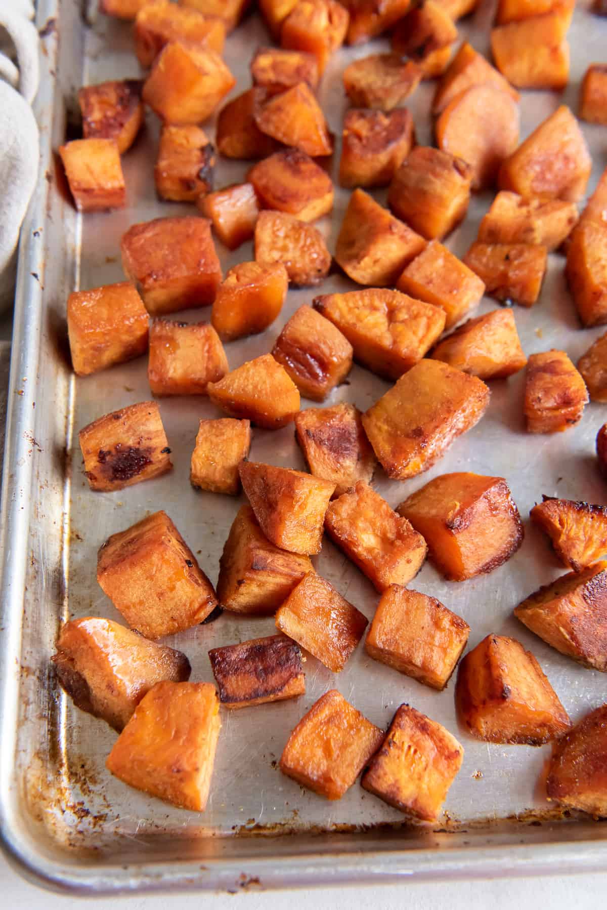 Roasted sweet potatoes spread out on a baking sheet.