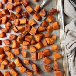 A top down shot of a spatula resting under roasted sweet potatoes on a baking sheet.