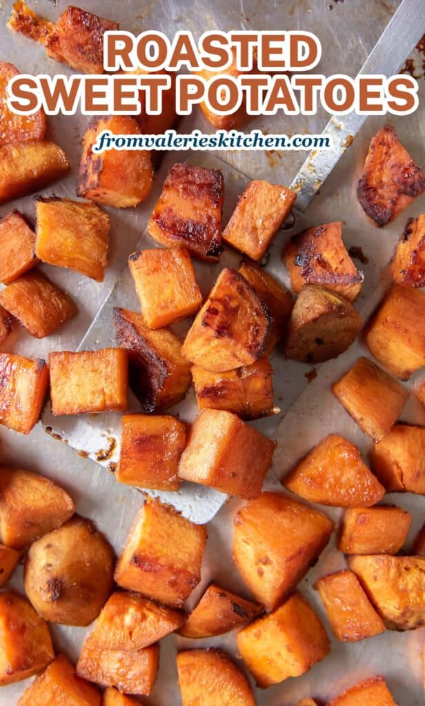 A close up top down shot of a spatula resting under roasted sweet potatoes on a baking sheet with text.