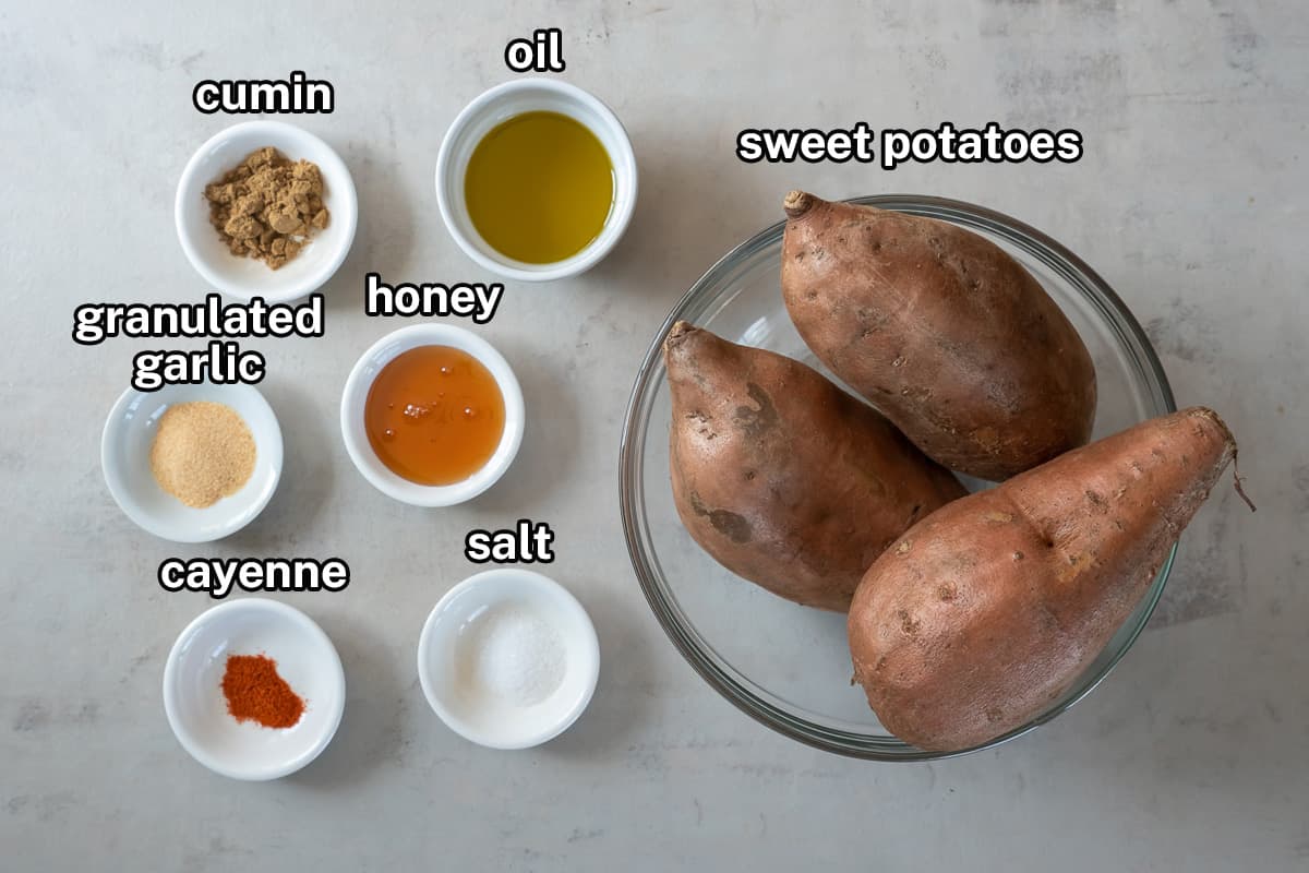 Sweet potatoes and small bowls of ingredients to make roasted sweet potatoes with text.
