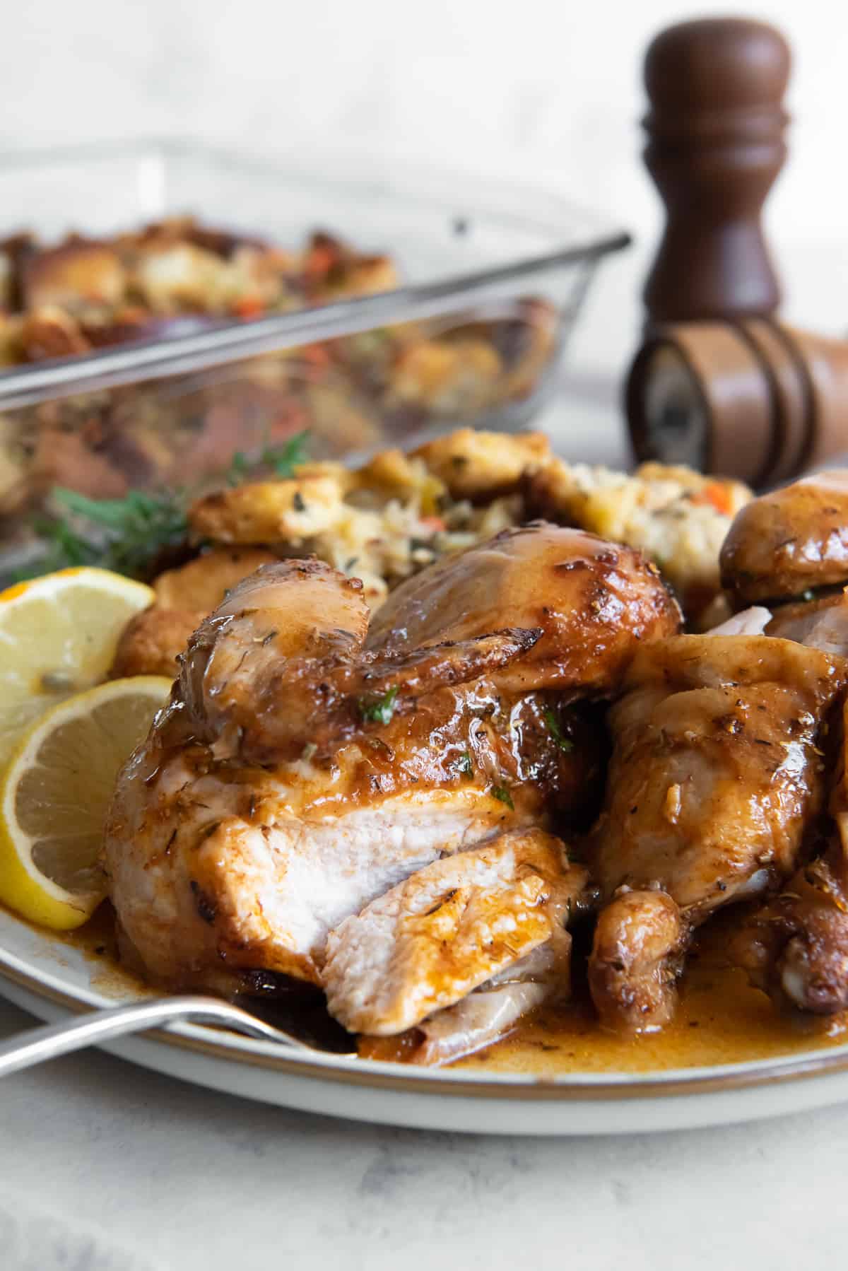 A fork on a plate with a sliced cornish game hen with gravy.