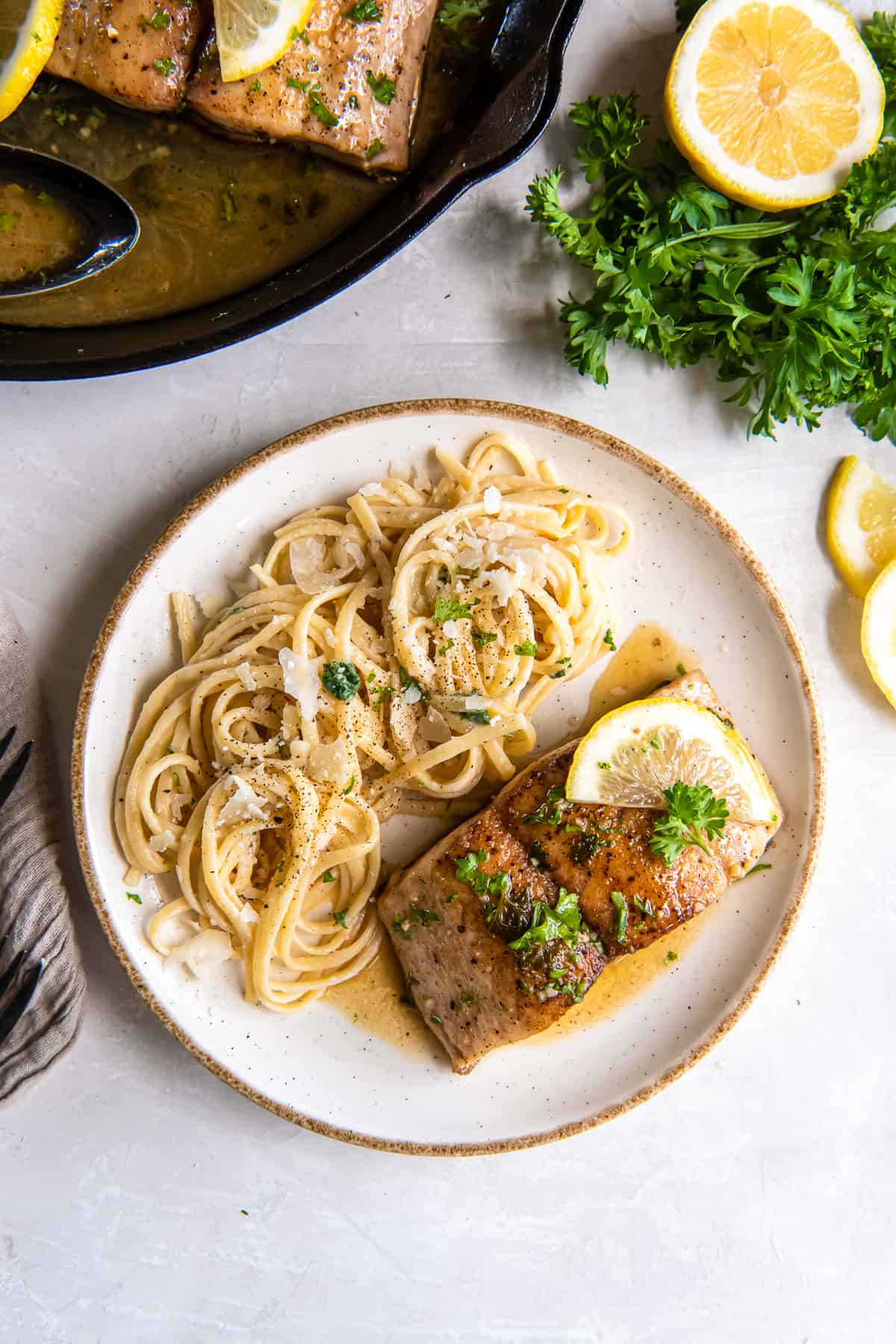 A top down shot of a white plate with a mahi mahi fillet and pasta.