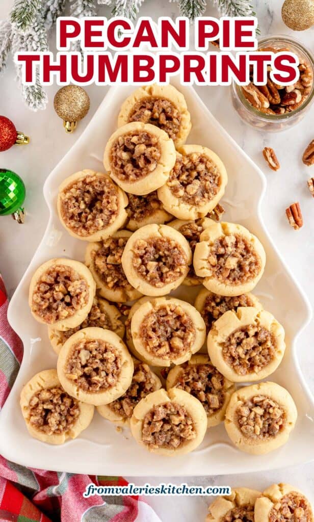 Pecan Pie Thumbprint Cookies on a Christmas tree shaped platter surrounded by ornaments with text.