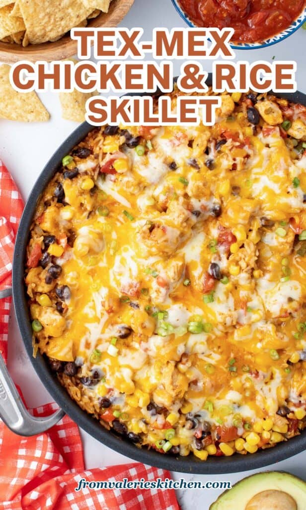 A top down shot of a skillet filled with a chicken and rice mixture with melted cheese with text.